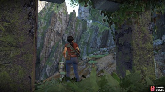 Climb the ruin to find the grapple hook point and swing across to the cave