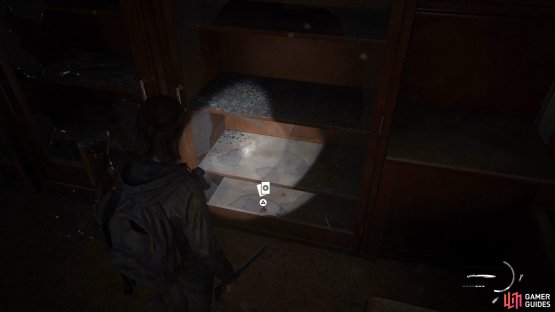 Go to the back of the room and smash the glass behind the counter to find a Trading Card