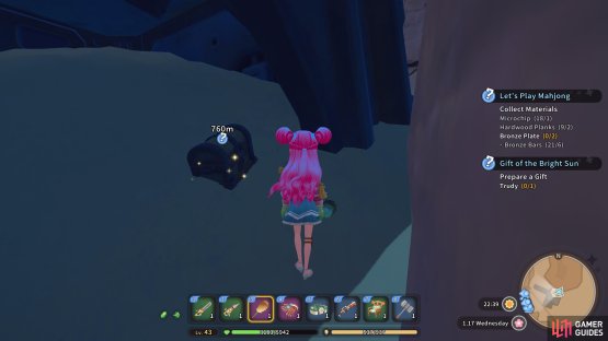 The chest is in the sand beside the metal tower.